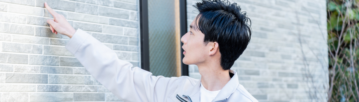男性社員が外壁を指差している